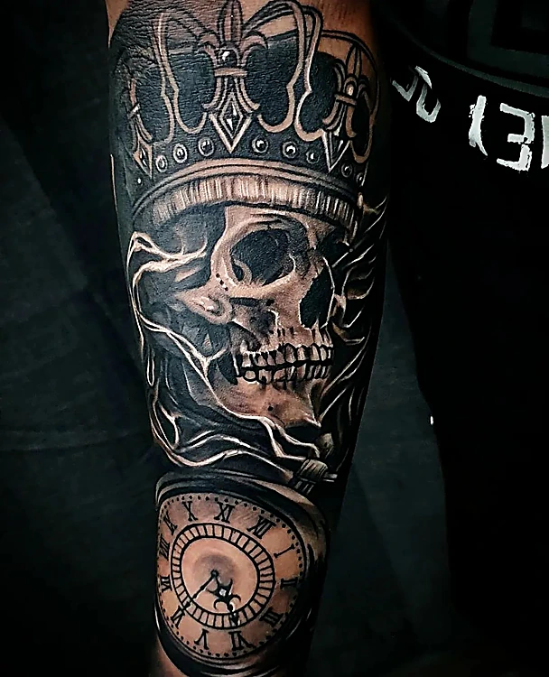 Calavera con corona y reloj de bolsillo en realismo negro y gris, en el antebrazo