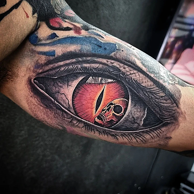 Ojo de reptil rojo en realismo con una calavera reflejada en la pupila, en el antebrazo
